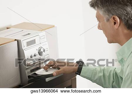 Side profile of a senior man inserting a CD into a CD player View Large Photo Image Picture - Side profile of a senior man inserting a CD into a CD player. Fotosearch