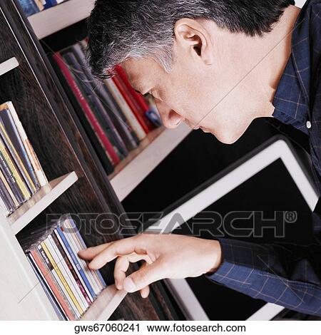 Stock Image - Side profile of a senior man looking for a CD. Fotosearch