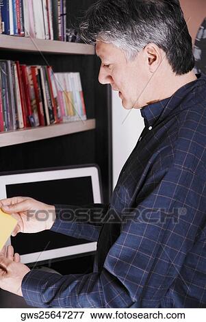 Stock Photo - Side profile of a senior man looking for a CD. Fotosearch