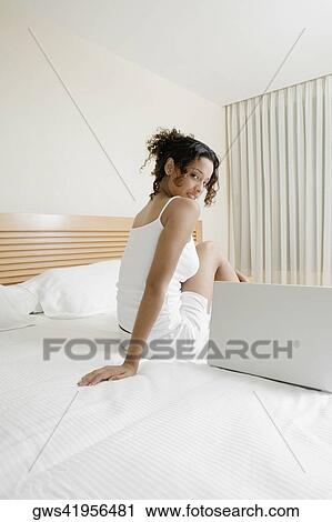 Side profile of a teenage girl sitting on the bed beside a laptop View Large Photo Image Stock Image - Side profile of a teenage girl sitting on the bed beside a laptop. Fotosearch
