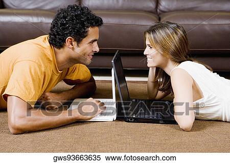 Side profile of a young couple lying down and using laptops View Large Photo Image Stock Photography - Side profile of a young couple lying down and using laptops. Fotosearch
