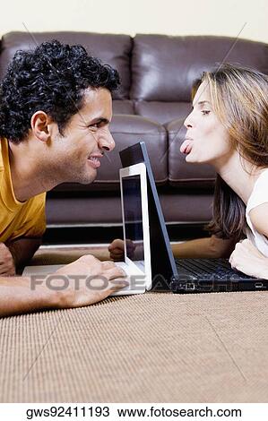 Stock Image - Side profile of a young couple using laptops. Fotosearch