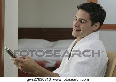 Side profile of a young man holding a remote control and smiling View Large Photo Image Stock Image - Side profile of a young man holding a remote control and smiling. Fotosearch