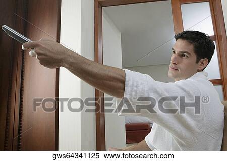 Side profile of a young man using a remote control View Large Photo Image Stock Photography - Side profile of a young man using a remote control. Fotosearch