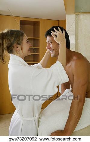 Stock Image - Side profile of a young woman adjusting a mid adult man's hair. Fotosearch