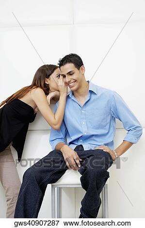 Side profile of a young woman whispering to a young man View Large Photo Image Stock Photo - Side profile of a young woman whispering to a young man. Fotosearch