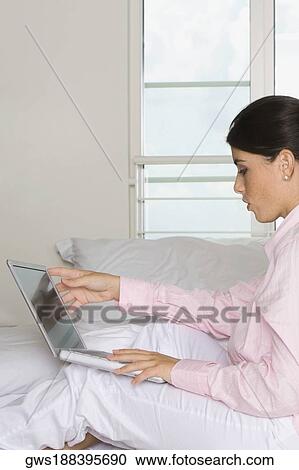 Stock Image - Side profile of a young woman using a laptop. Fotosearch