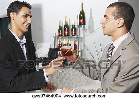 Picture - Side profile of two businessmen toasting their glasses. Fotosearch
