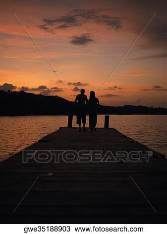 Silhouette of a man and a woman standing on a pier View Large Photo Image Stock Image - Silhouette of a man and a woman standing on a pier. Fotosearch