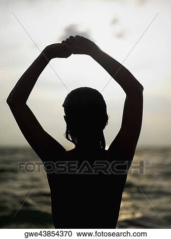 Silhouette of a young woman with her arms raised View Large Photo Image Stock Image - Silhouette of a young woman with her arms raised. Fotosearch