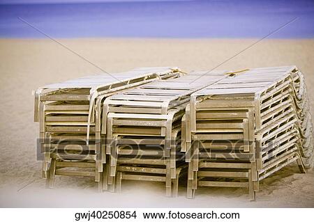 Stack of lounge chairs on the beach View Large Photo Image Picture - Stack of lounge chairs on the beach. Fotosearch