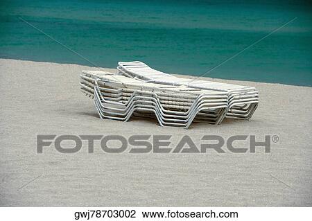 Stock Image - Stack of lounge chairs on the beach. Fotosearch