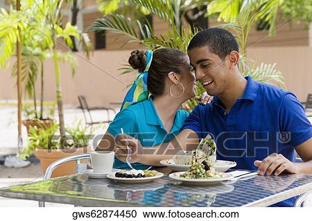 Teenage girl whispering into a young man's ear View Large Photo Image Stock Image - Teenage girl whispering into a young man's ear. Fotosearch