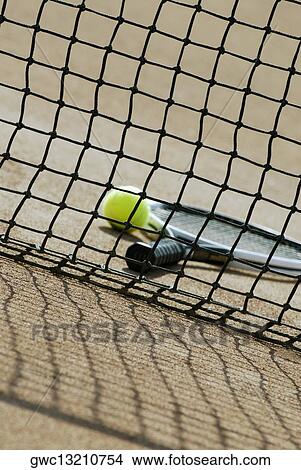 Tennis ball and a tennis racket behind a tennis net View Large Photo Image Picture - Tennis ball and a tennis racket behind a tennis net. Fotosearch