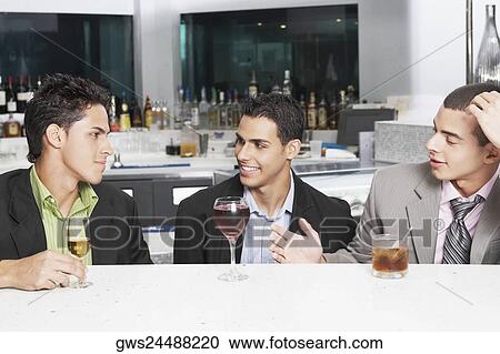 Three businessmen sitting at a bar counter View Large Photo Image Stock Image - Three businessmen sitting at a bar counter. Fotosearch