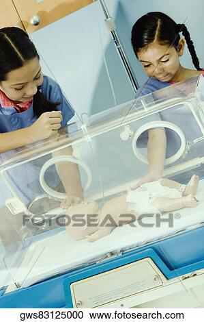 Two girls touching a doll in an incubator View Large Photo Image Stock Image - Two girls touching a doll in an incubator. Fotosearch