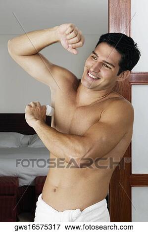 Young man applying deodorant under his armpit View Large Photo Image Stock Photo - Young man applying deodorant under his armpit. Fotosearch
