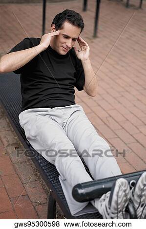 Young man doing sit-ups on a weight bench View Large Photo Image Stock Photo - Young man doing sit-ups on a weight bench. Fotosearch