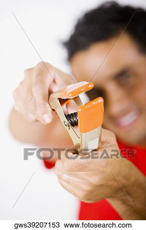 Young man holding a clamp View Large Photo Image Stock Image - Young man holding a clamp. Fotosearch