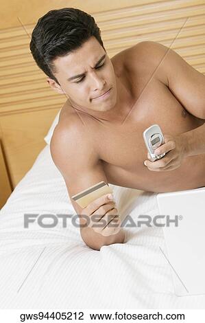 Young man holding a credit card and a mobile phone View Large Photo Image Stock Image - Young man holding a credit card and a mobile phone. Fotosearch