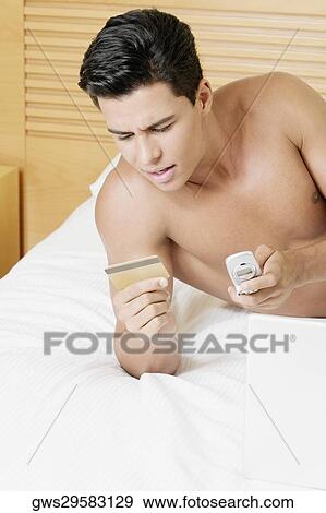 Young man holding a credit card and a mobile phone View Large Photo Image Stock Photo - Young man holding a credit card and a mobile phone. Fotosearch