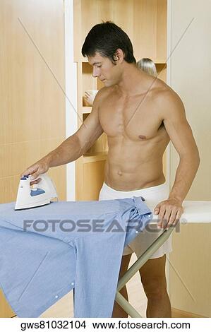 Young man ironing a shirt View Large Photo Image Picture - Young man ironing a shirt. Fotosearch