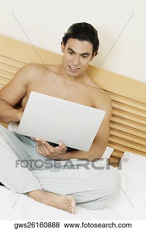 Young man using a laptop View Large Photo Image Stock Photo - Young man using a laptop. Fotosearch
