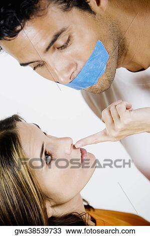 Stock Image - Young man with adhesive tape on his mouth and mid adult woman looking at him. Fotosearch