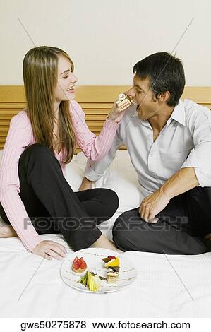 Young woman feeding cake to a mid adult man View Large Photo Image Stock Photo - Young woman feeding cake to a mid adult man. Fotosearch