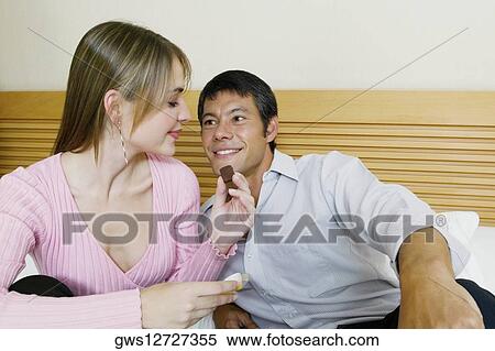 Stock Photography - Young woman feeding chocolate to a mid adult man . Fotosearch