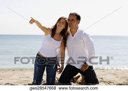 Young woman pointing forward to a mid adult man on the beach View Large Photo Image Stock Photo - Young woman pointing forward to a mid adult man on the beach. Fotosearch