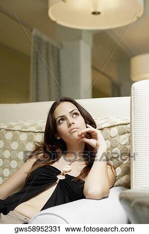 Young woman sitting on a couch and thinking View Large Photo Image Stock Image - Young woman sitting on a couch and thinking. Fotosearch