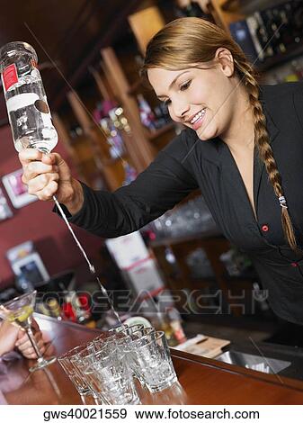 Stock Photo - Bartender making drinks at a bar counter. Fotosearch