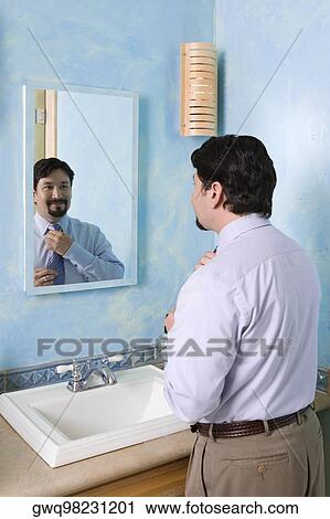 Businessman adjusting his tie in the bathroom View Large Photo Image Stock Image - Businessman adjusting his tie in the bathroom. Fotosearch