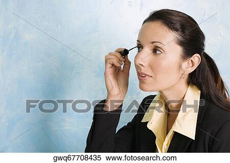 Businesswoman applying mascara on her eyes View Large Photo Image Stock Photography - Businesswoman applying mascara on her eyes. Fotosearch