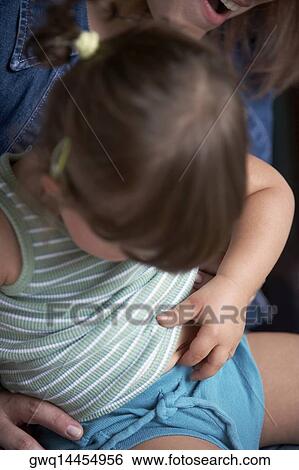 Close-up of a baby girl sitting on her mother's lap View Large Photo Image Stock Photograph - Close-up of a baby girl sitting on her mother's lap. Fotosearch