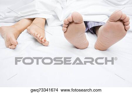 Picture - Close-up of a couple's feet on the bed. Fotosearch