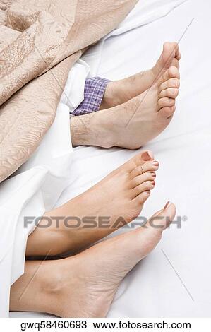 Stock Image - Close-up of a couple's feet on the bed. Fotosearch