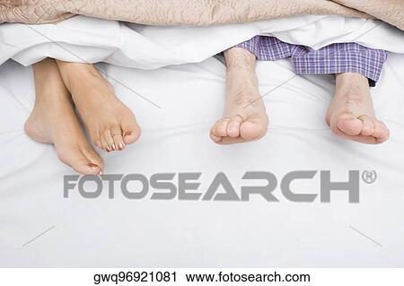 Stock Image - Close-up of a couple's feet on the bed. Fotosearch