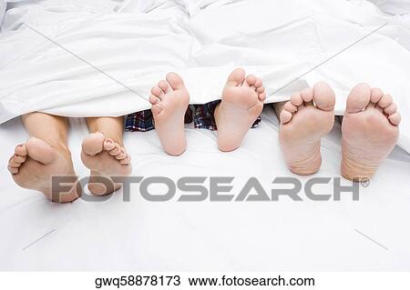 Close-up of a couple's feet with their child on the bed View Large Photo Image Stock Image - Close-up of a couple's feet with their child on the bed. Fotosearch