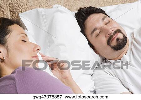 Stock Photo - Close-up of a mid adult couple sleeping on the bed. Fotosearch