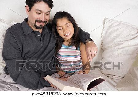 Close-up of a mid adult man and his daughter reading a book View Large Photo Image Stock Photo - Close-up of a mid adult man and his daughter reading a book. Fotosearch