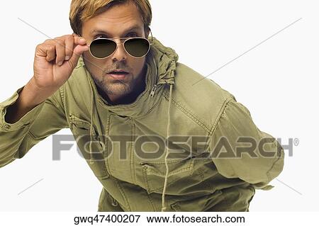 Close-up of a mid adult man peeking over his sunglasses View Large Photo Image Stock Photo - Close-up of a mid adult man peeking over his sunglasses. Fotosearch
