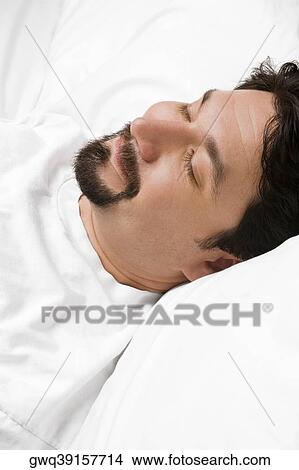 Close-up of a mid adult man sleeping on the bed View Large Photo Image Picture - Close-up of a mid adult man sleeping on the bed. Fotosearch