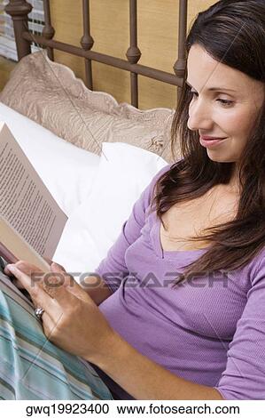 Stock Image - Close-up of a mid adult woman reading a book. Fotosearch