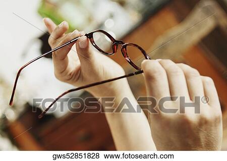 Close-up of a person holding eyeglasses View Large Photo Image Stock Photo - Close-up of a person holding eyeglasses. Fotosearch