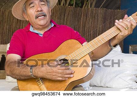 Picture - Close-up of a senior man playing a guitar and singing. Fotosearch