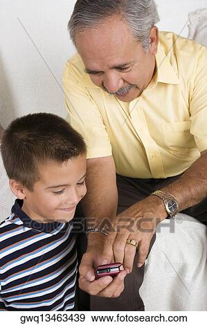 Close-up of a senior man showing a mobile phone to his grandson View Large Photo Image Stock Photo - Close-up of a senior man showing a mobile phone to his grandson. Fotosearch