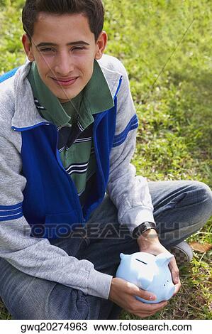 Close-up of a teenage boy holding a piggy bank View Large Photo Image Stock Image - Close-up of a teenage boy holding a piggy bank. Fotosearch