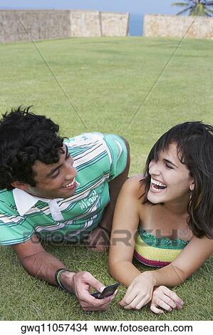 Picture - Close-up of a young couple lying in a lawn and smiling. Fotosearch